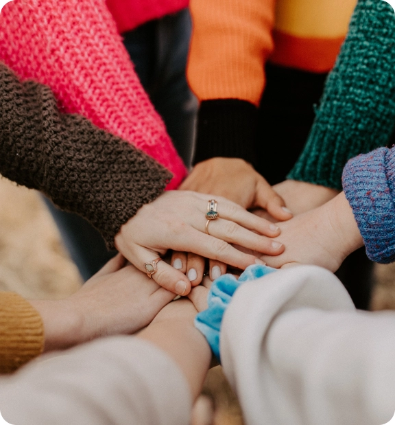close-up shot of a group of youths as they stack hands on each other in a circle